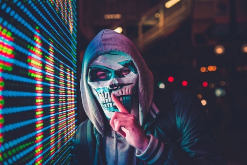 Genrebild för att illustrera cyberbrott och säkerhetsintrång: En maskerad person vid en datorskärm.