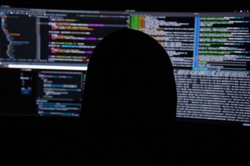 Genrefoto: Bakhuvudet på en person vid dataskärmar, bilden illustrerar bluffmejl och cybersäkerhet
