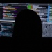 Genrefoto: Bakhuvudet på en person vid dataskärmar, bilden illustrerar bluffmejl och cybersäkerhet