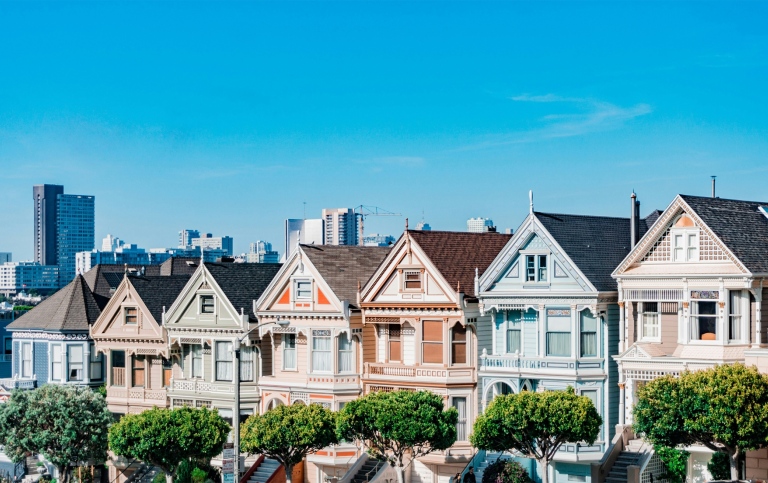 The “Painted Ladies” wooden houses in light colors, modern tall buildings in the background.